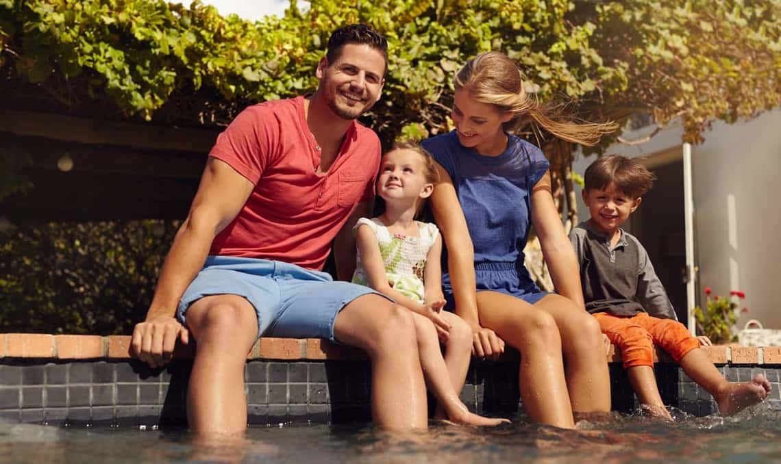family of four with feet in pool