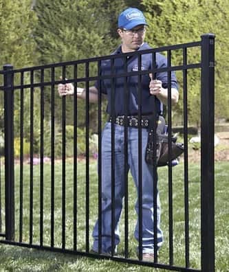 man installing section of iron fence